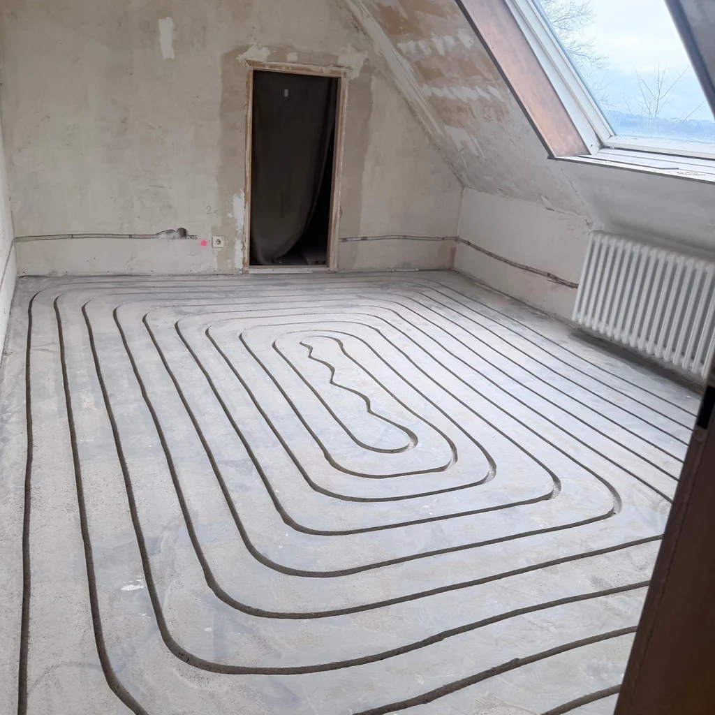 Gefräste Heizkanäle im Dachgeschoss; unter dem Dachfenster ist noch ein Heizkörper montiert.