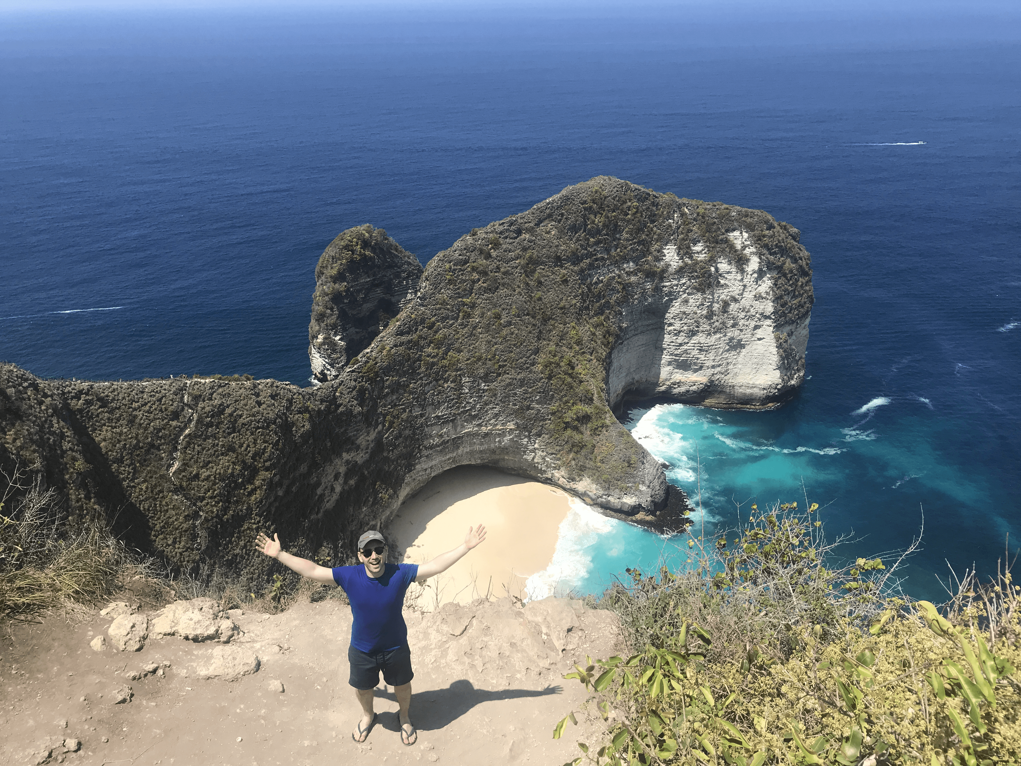 Picture of Adrian stood on the edge of an island, smiling in front of the sea.
