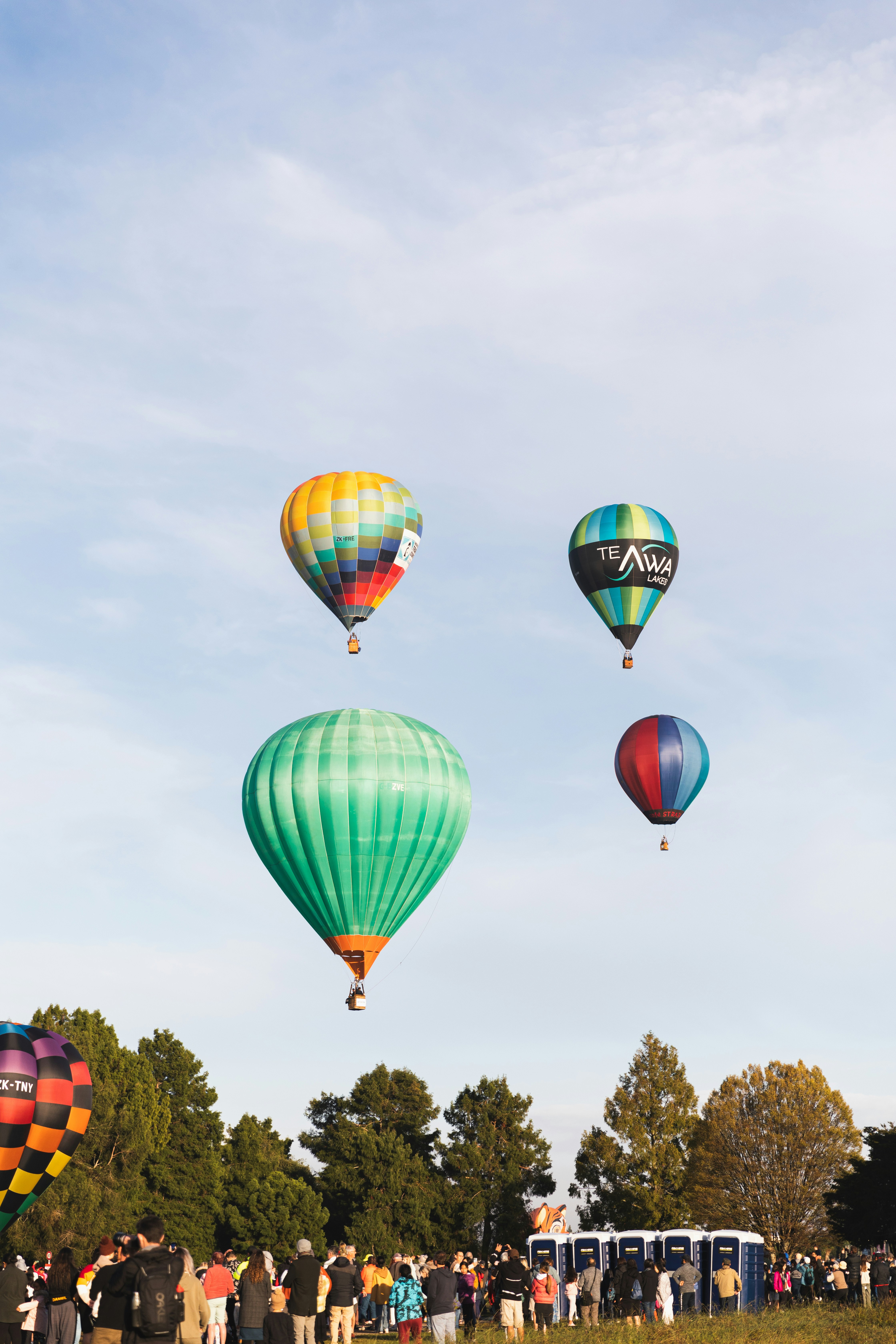 a group of people watching hot air balloons in the sky