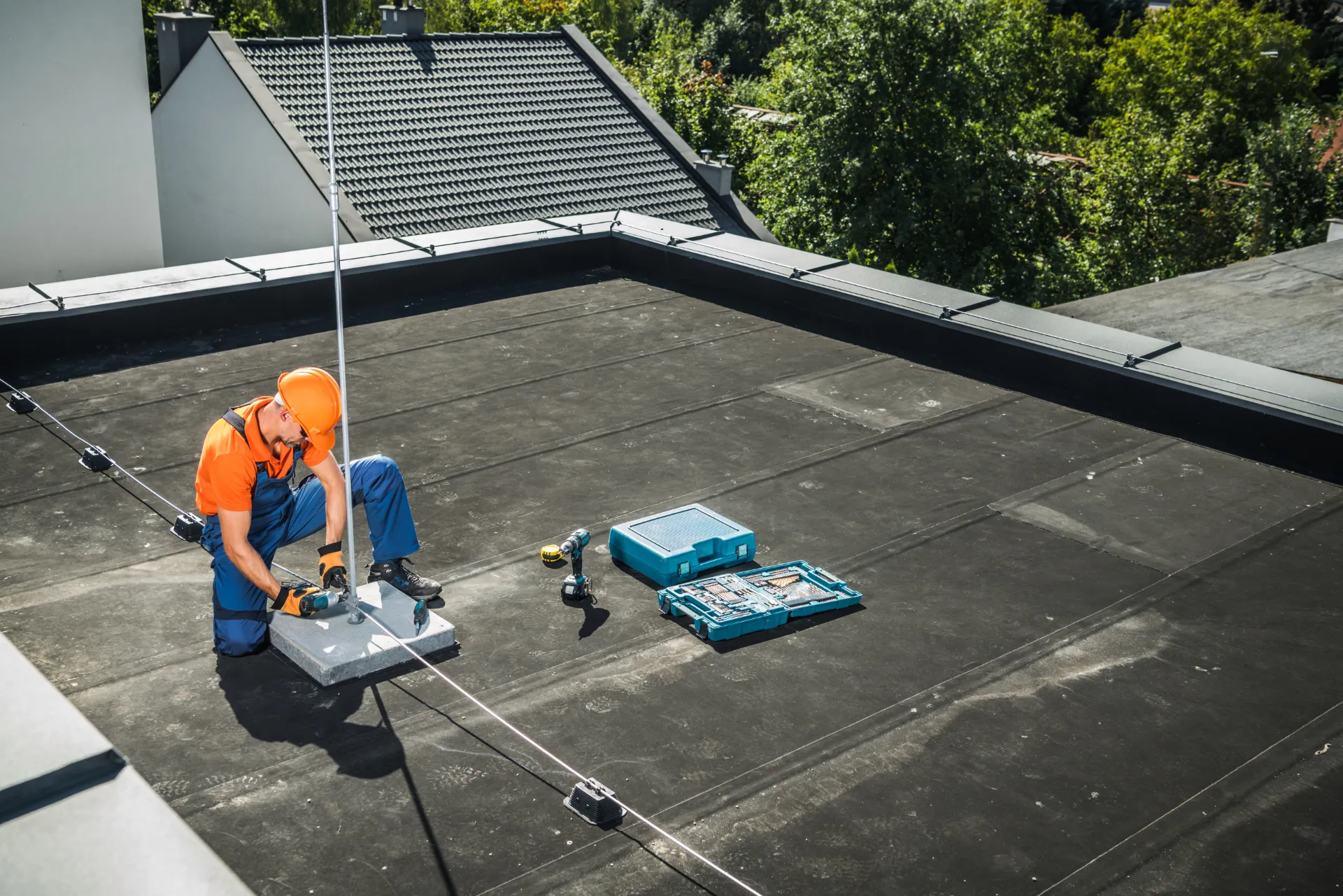 Ein Monteur der gerade einen Blitzableiter auf einem Hausdach installiert.