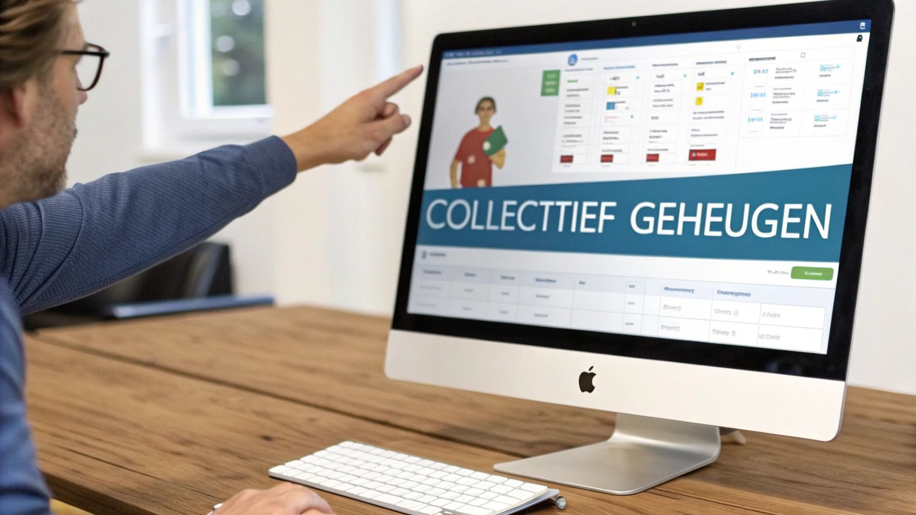 Persoon wijst naar een iMac-scherm met daarop de tekst 'Collecttief Geheugen' en een software-interface op een houten bureau.