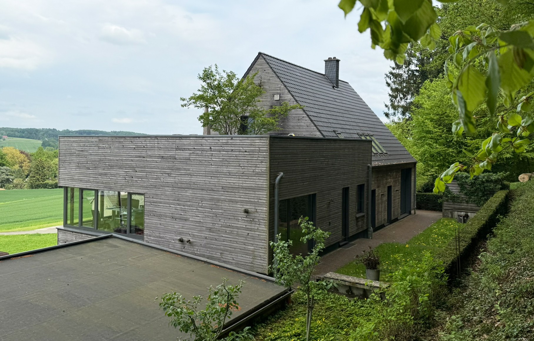 Das nachhaltige Bürogebäude von Beinker Architektur mit anschließendem Wohnhaus mit moderner Holzfassade im Grünen – Beispiel für energieeffiziente Architektur von Beinker Architektur.