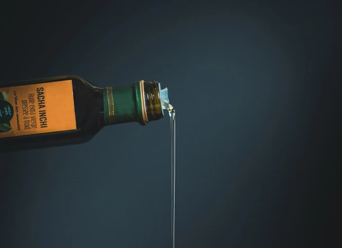 Olive oil pouring from a glass bottle