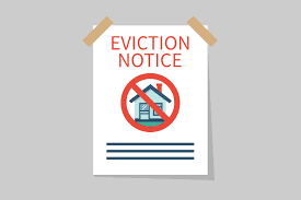 A white paper notice taped to a gray background has the red text "EVICTION NOTICE" at the top. Below the text is a red circle with a line through it (a prohibition sign) over a small illustration of a house, visually representing the banning of evictions.