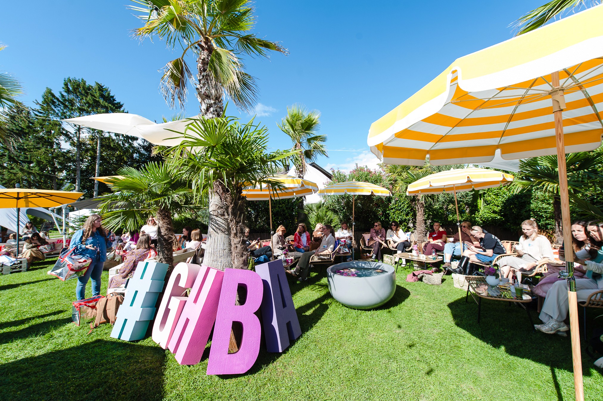 Teilnehmerinnen entspannen sich unter Sonnenschirmen im Garten