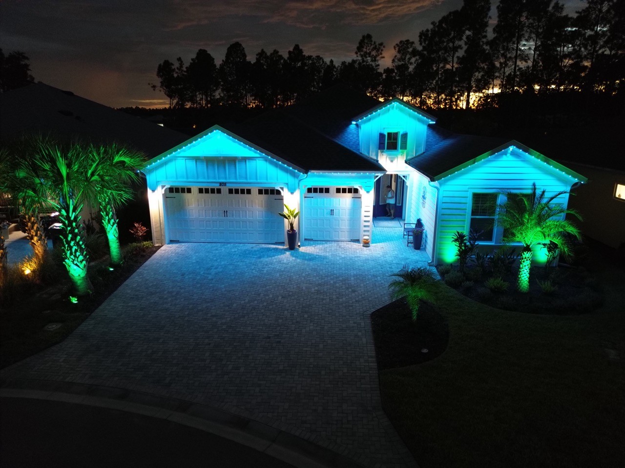 Color-changing permanent lighting illuminating driveway and landscaping