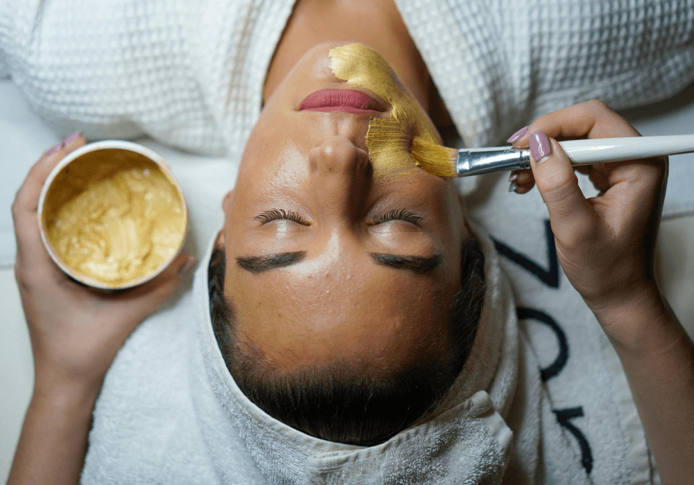 A woman getting a facial treatment as a spa with yellow facial cream
