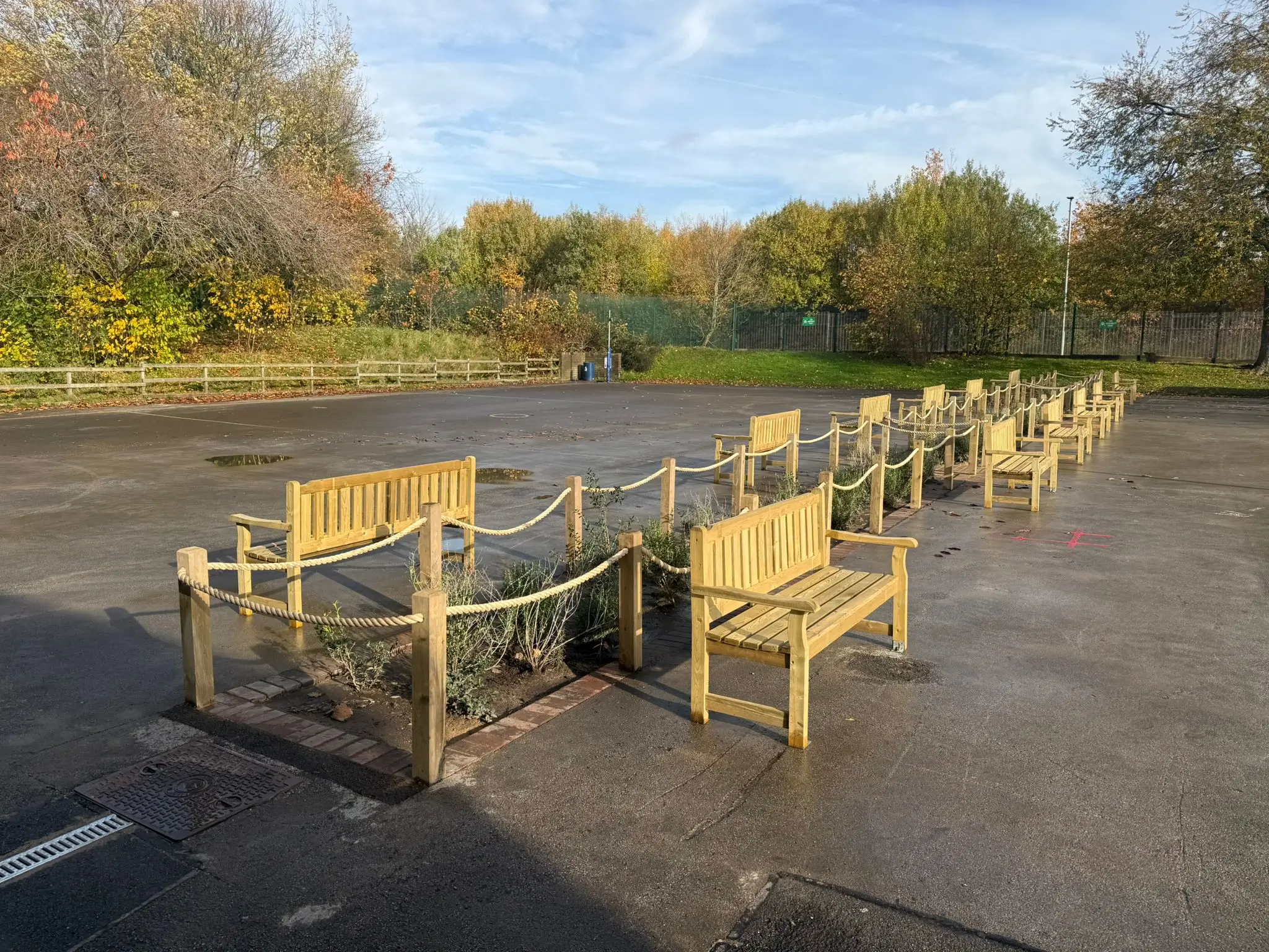 Round tables with chairs set up outdoors, surrounded by trees and a clear blue sky.
