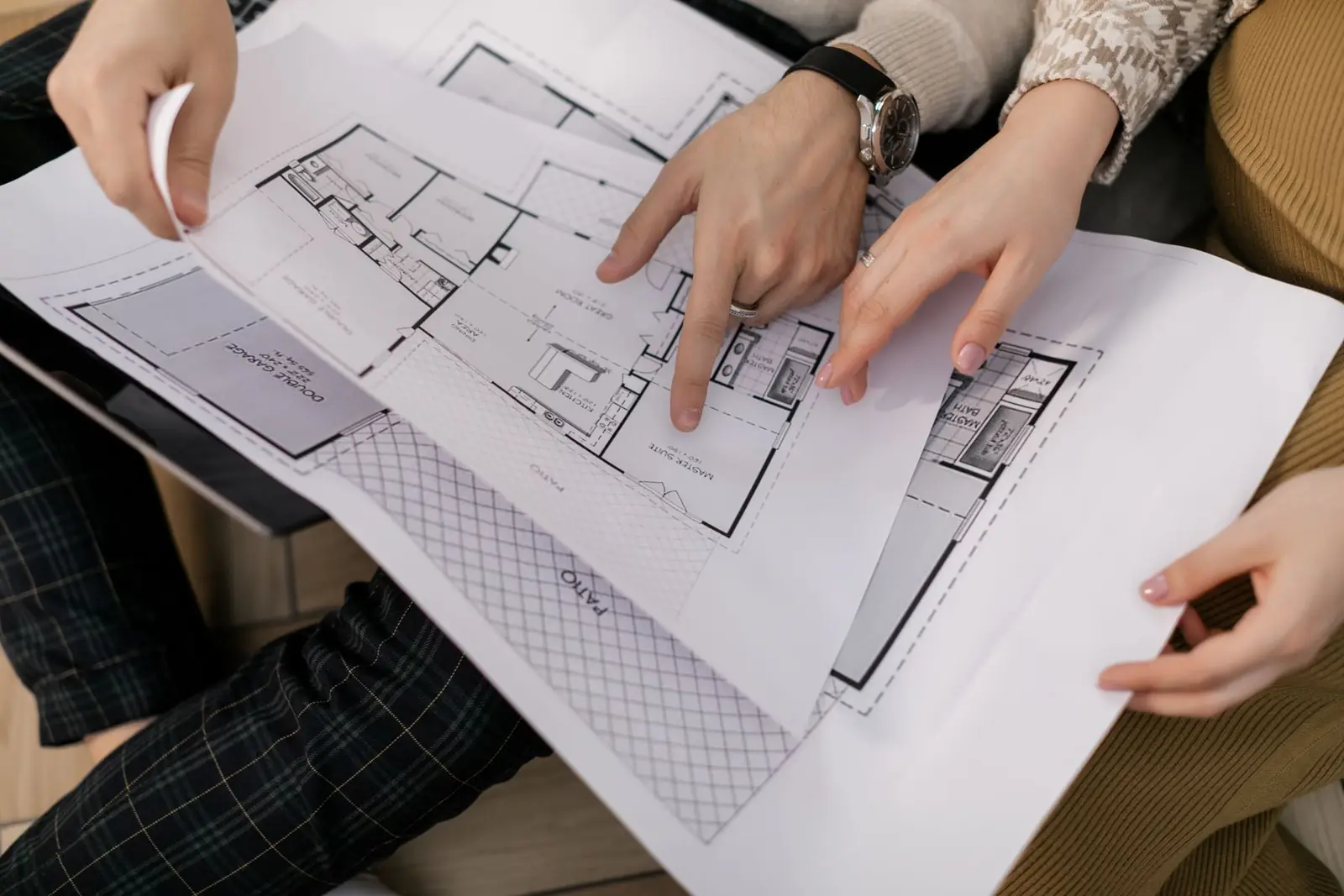 Two people pointing at a printed floor plan