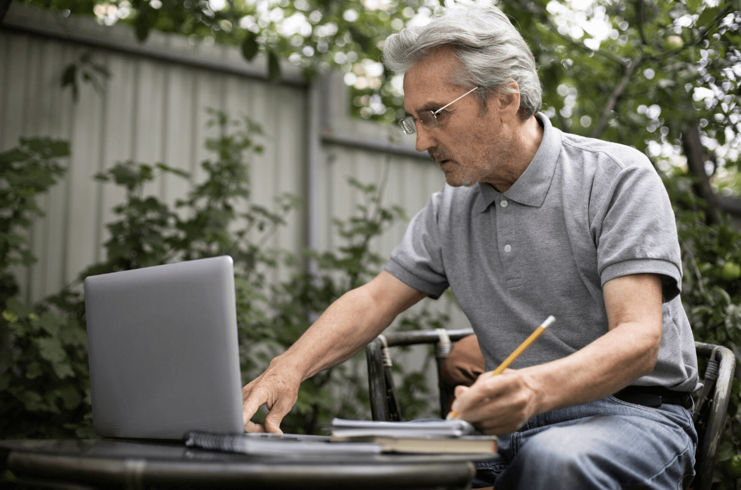 Older man working on laptop in his garden