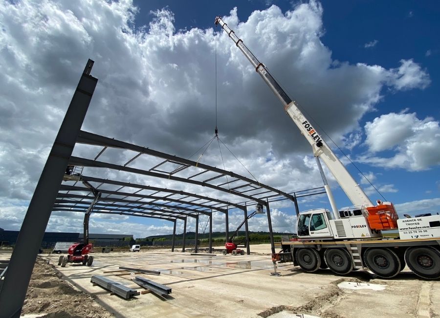 Levage de poutres en acier par grue sur chantier de bâtiment professionnel.