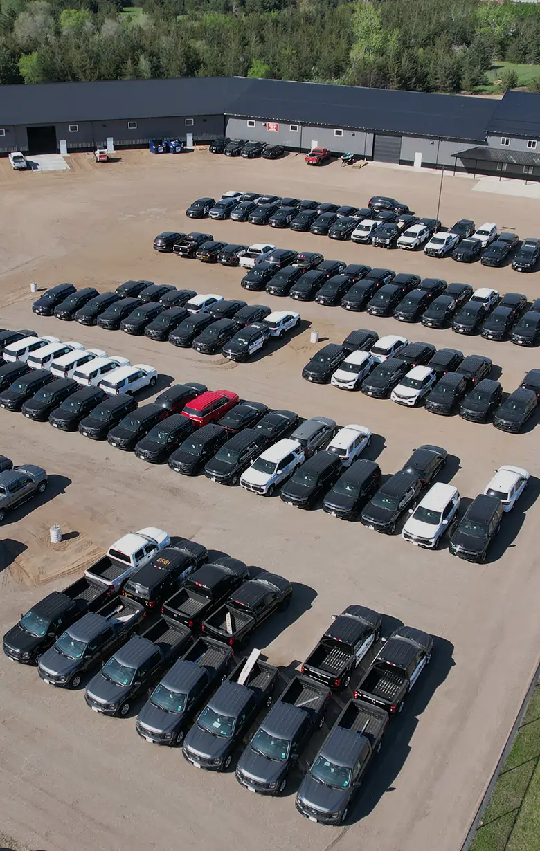Aerial view of the Guardian Fleet Safety facility with dozens of vehicles parked in rows outside the build shop