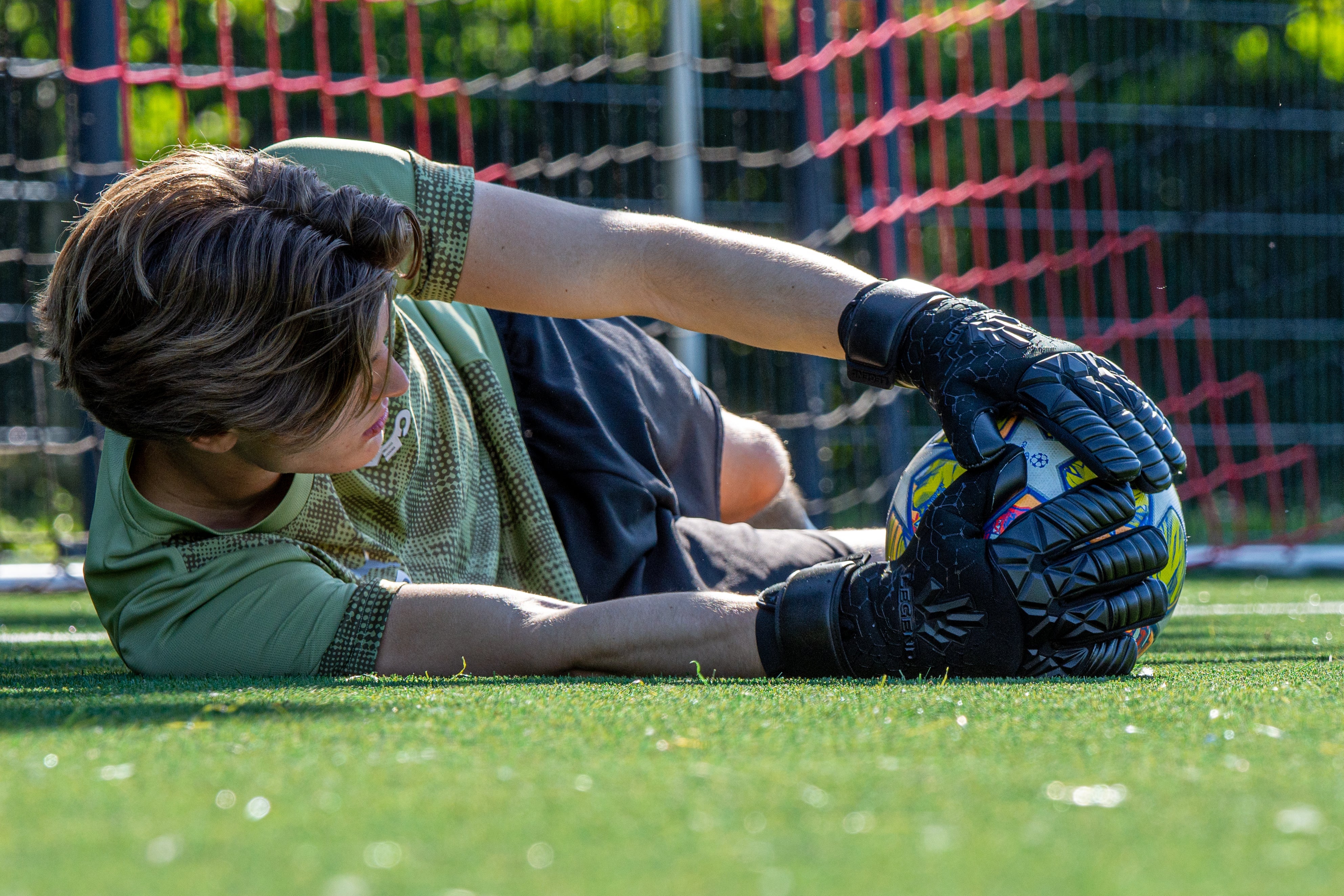 Keeper wearing THE BOMB goalkeeper gloves making a save