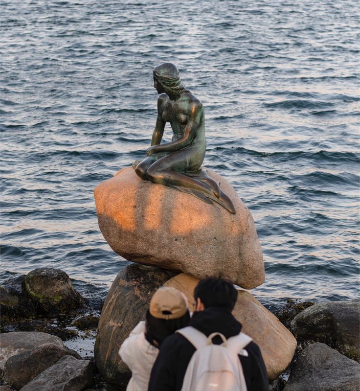 A statue of a woman sitting on top of a rock