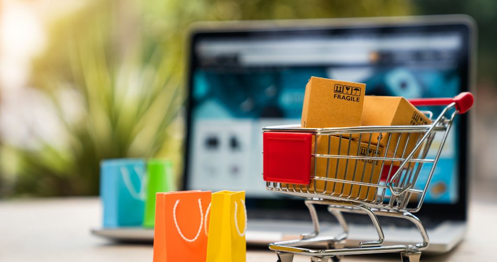 Shopping cart with packages in front of a laptop for online business