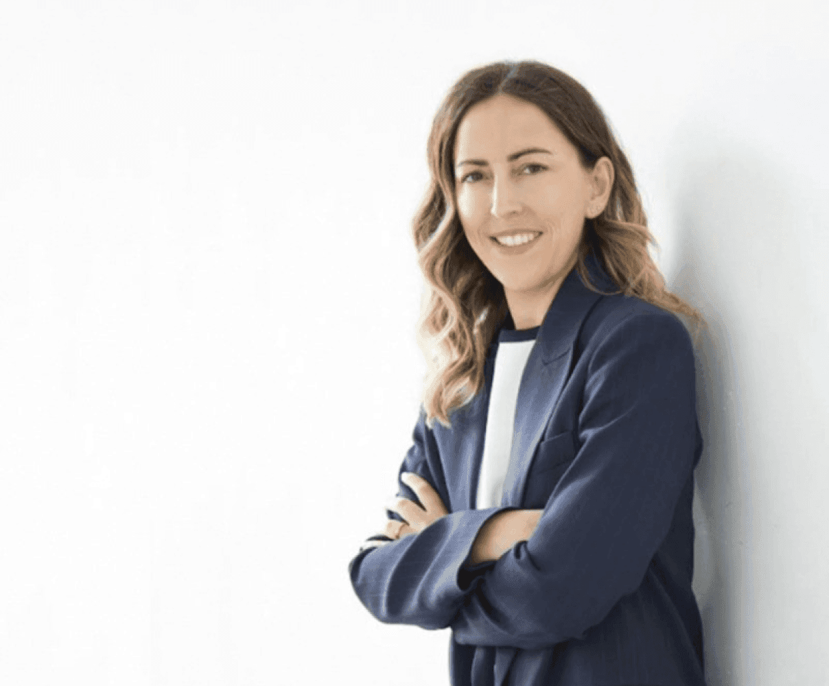 Professional woman in blue blazer leaning on wall