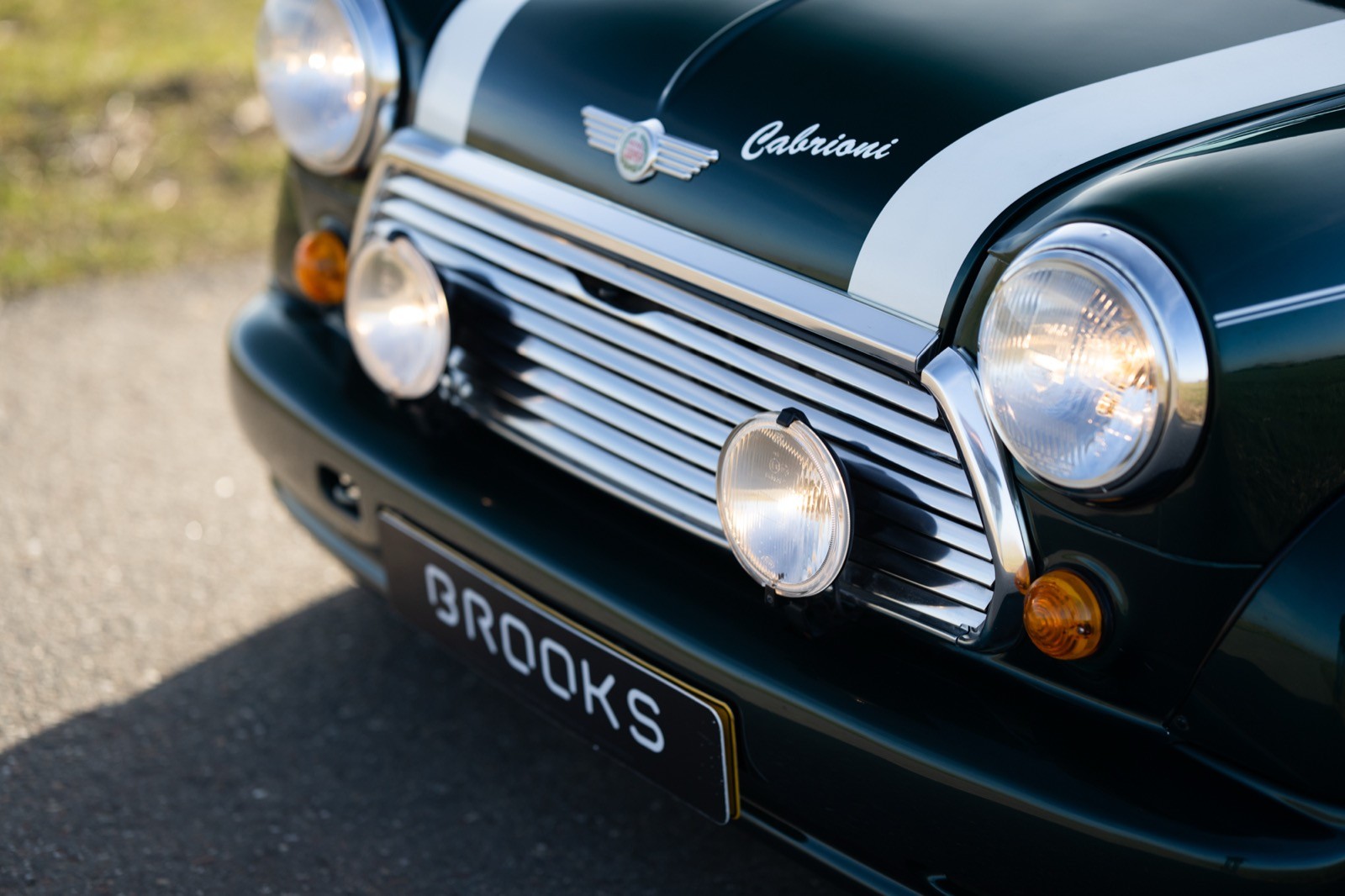Close-up of a classic green car's front grille and headlights, featuring chrome accents and a vintage design.