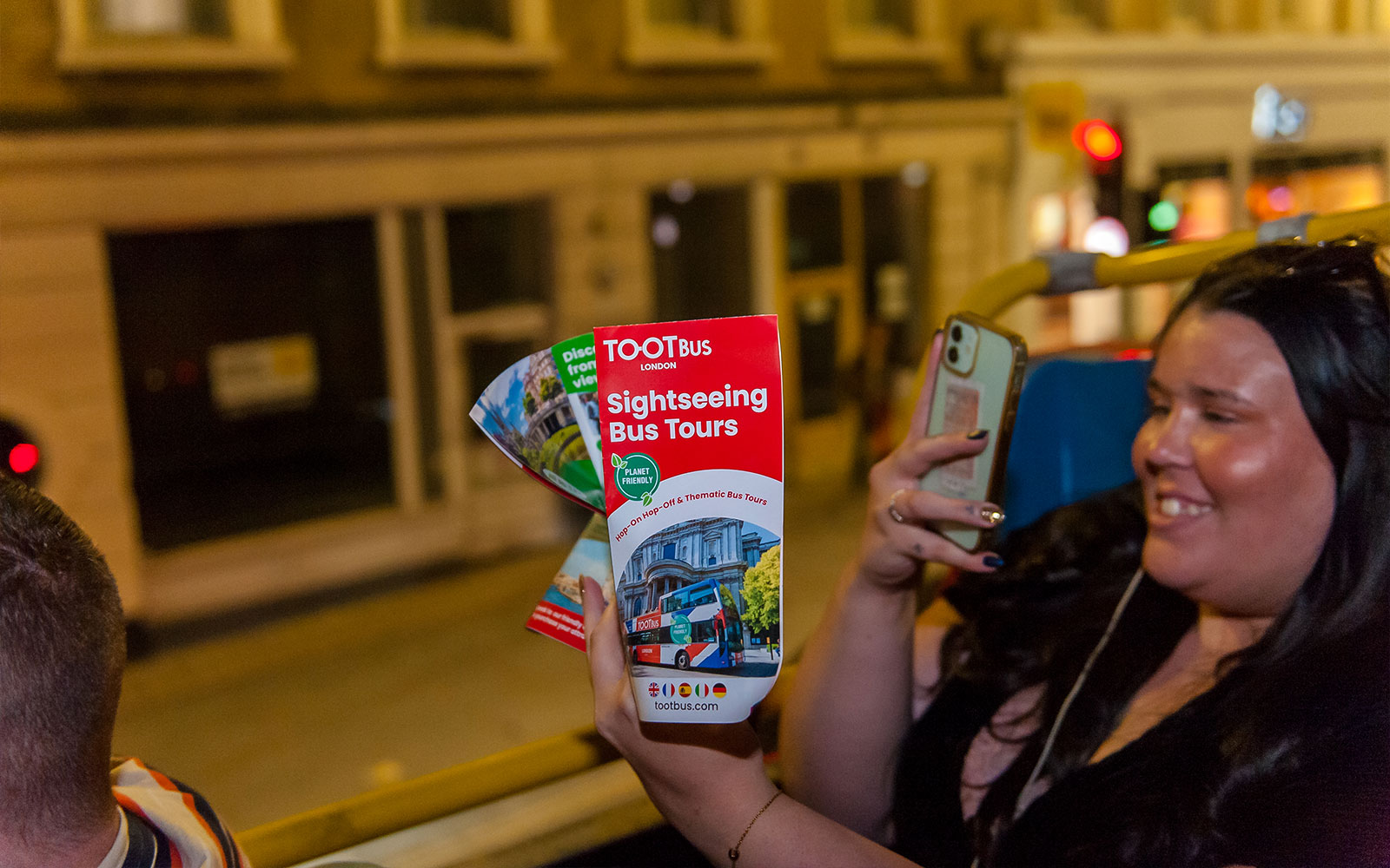 Brochure de visite guidée en bus touristique tenue par une personne lors d'une visite nocturne à Londres.