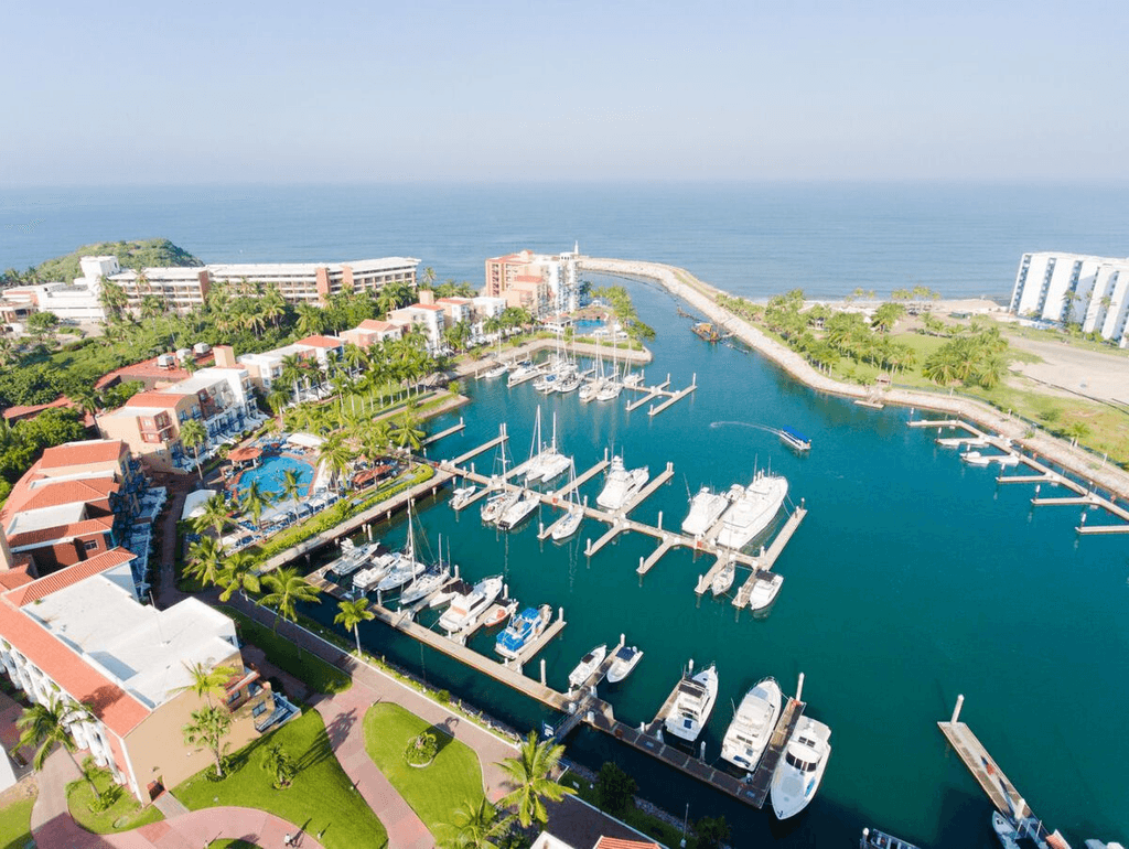 Couple standing on a balcony with binoculars in hand looking out over the ocean