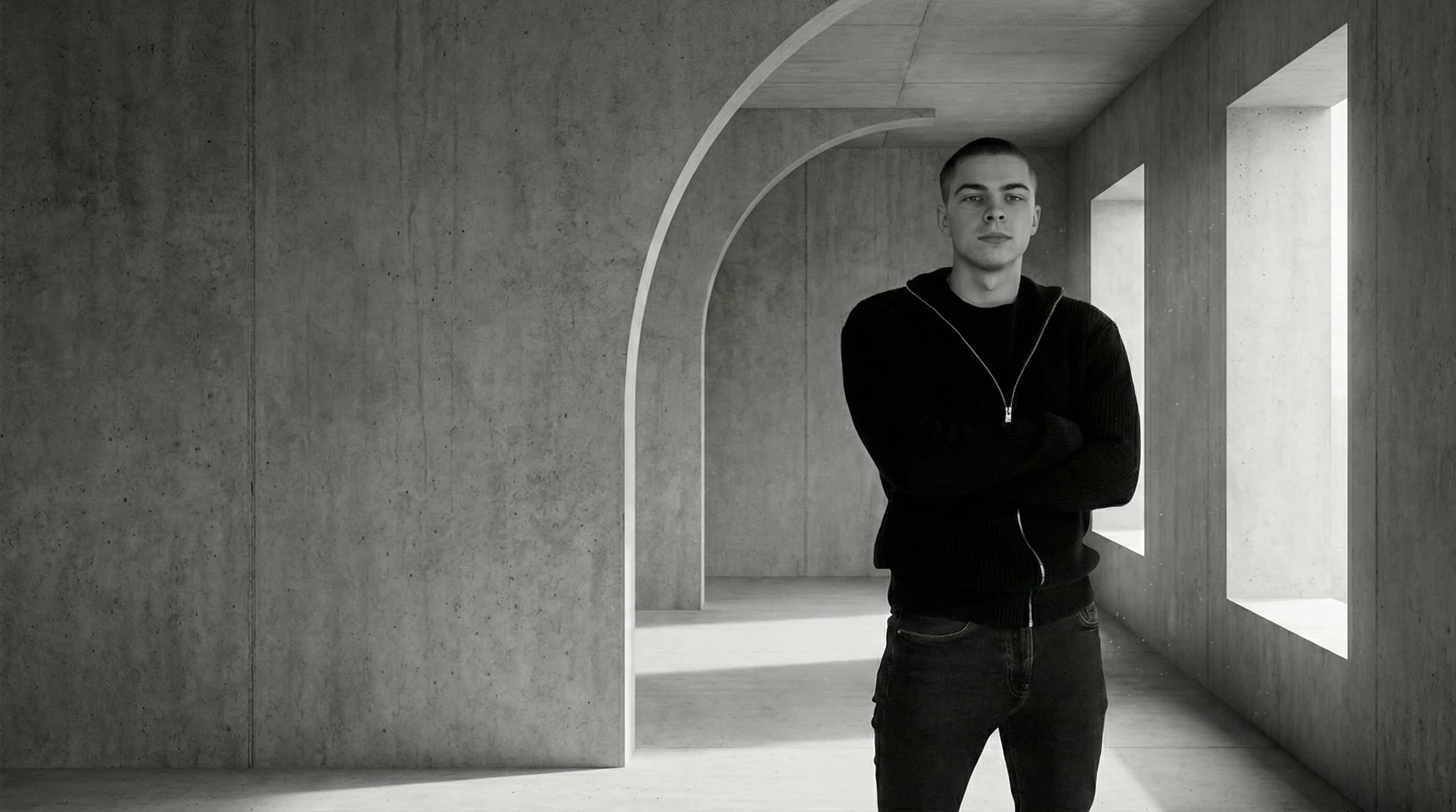 Székely Soma webdesigner portréja modern, minimalista beton építészeti környezetben, fekete ruhában. A kép a letisztult és prémium design szemléletet tükrözi.