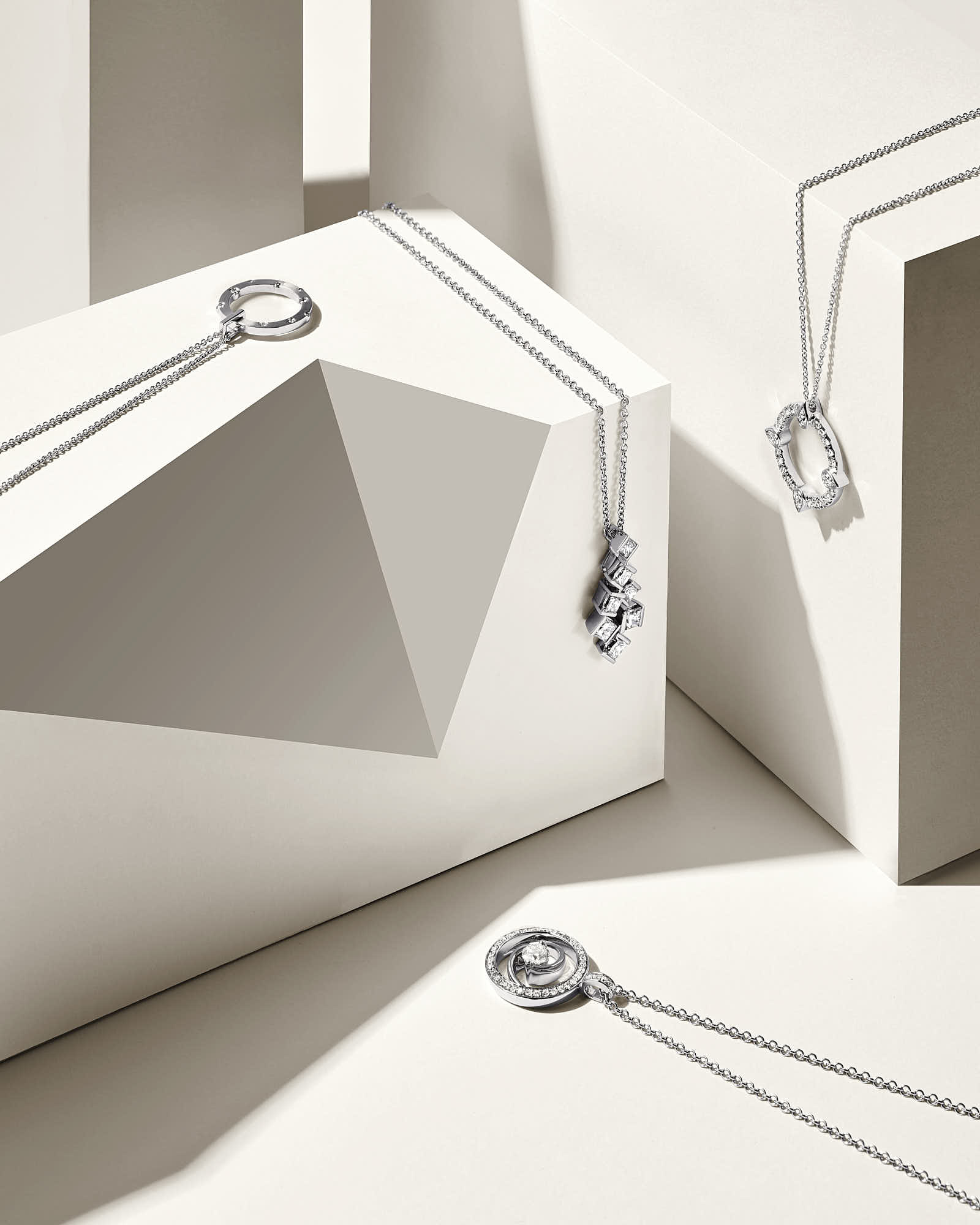 Minimalist composition featuring geometric shapes and elegant jewelry pieces arranged on a neutral background.