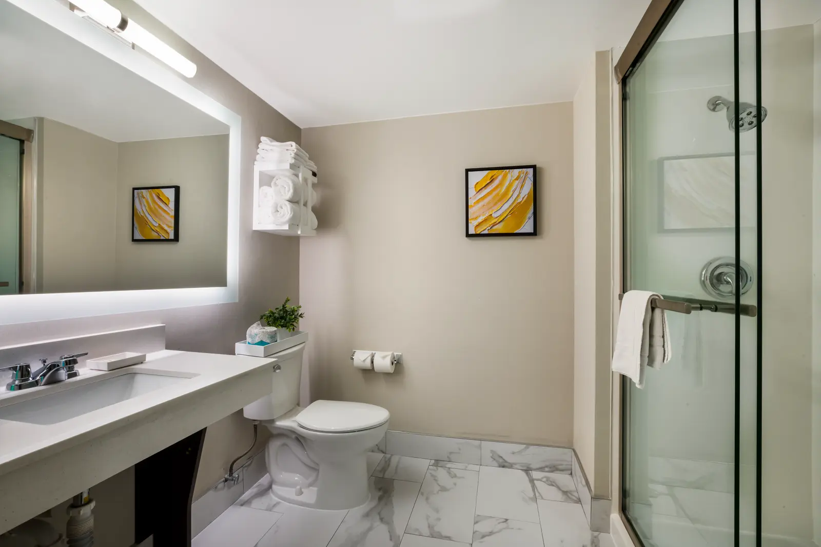 Modern hotel room with two beds, white linens, wood floor, and gold accent wall.