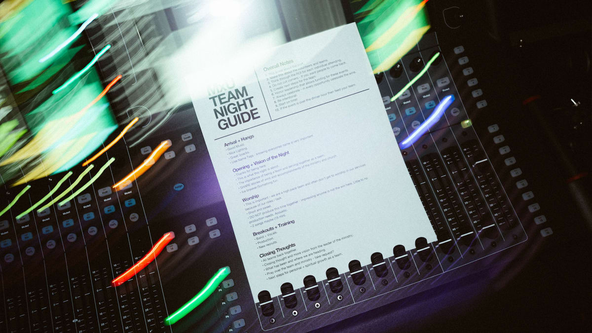 Cover image for the free MxU worship ministry resource, titled 'Team Night Guide,' featuring the printed guide on a sound mixing console, colorful lights behind.