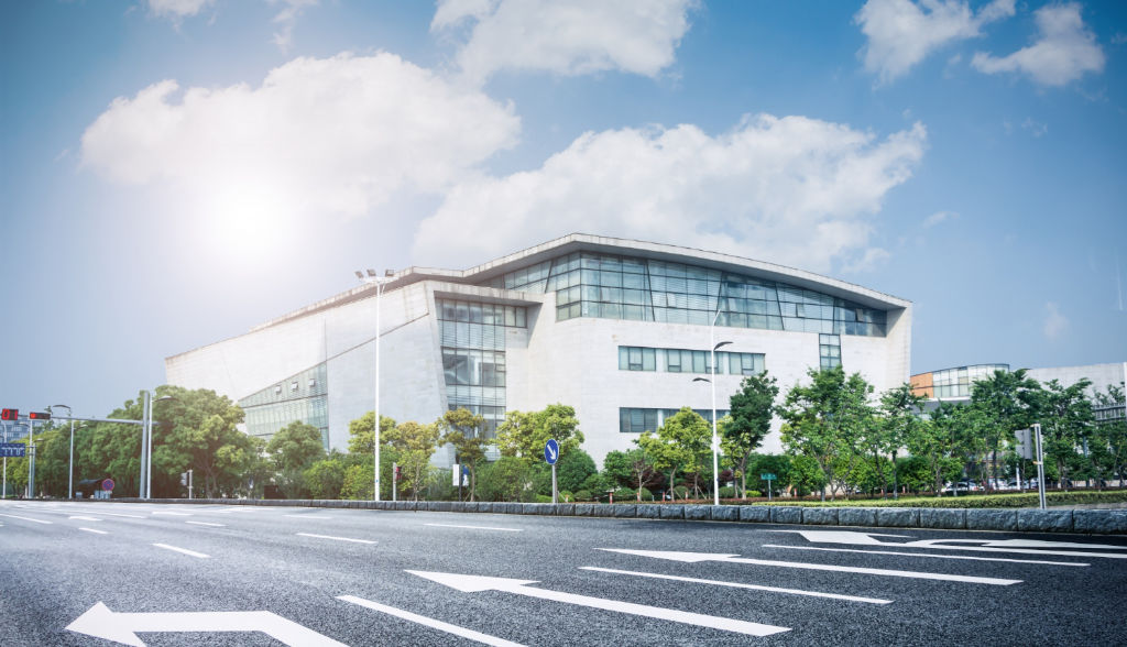 An empty road with a hospital in the background.