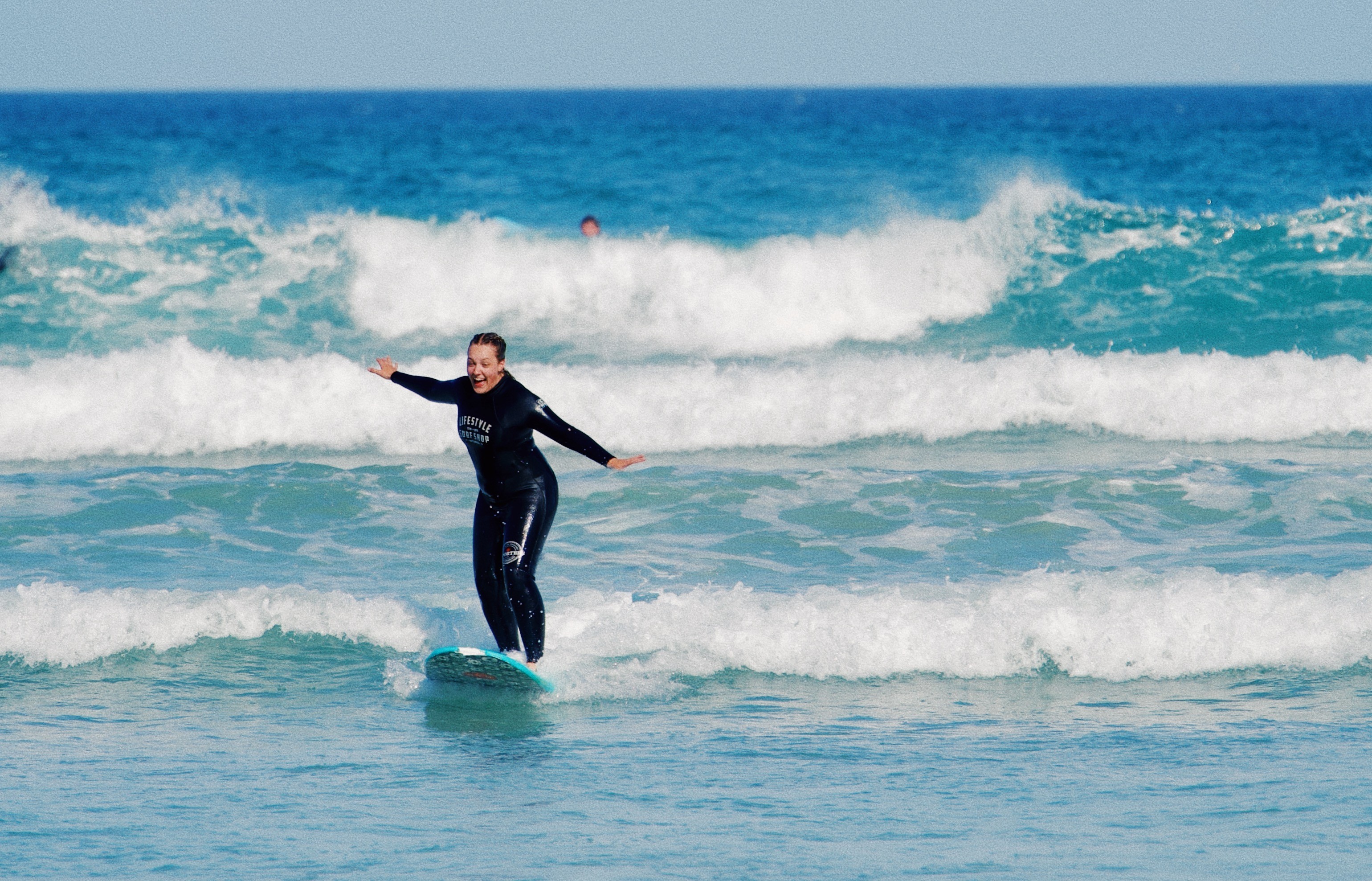 A female beginner surfer riding a wave during her beginner surf lesson in Muizenberg, Cape Town. Eine Surf Anfängerin während ihrer ersten Surfstunde in Muizenberg, Kapstadt