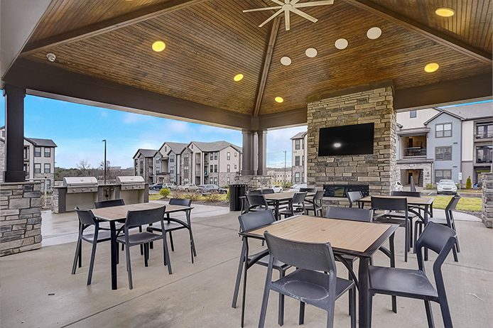 Open-air covered resident pavilion with a wooden ceiling, stone fireplace, and seating areas, demonstrating M-Fire's protection for wood-frame common spaces.