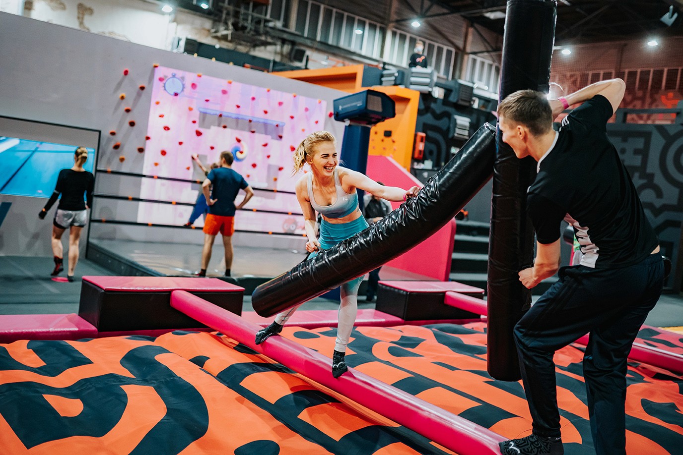 Grupa ludzi bawiących się w parku trampolin, korzystając z oferty parku, obejmującej również sprzedaż produktów i udostępnienie formularza rejestracyjnego online systemu rezerwacji Going. Places