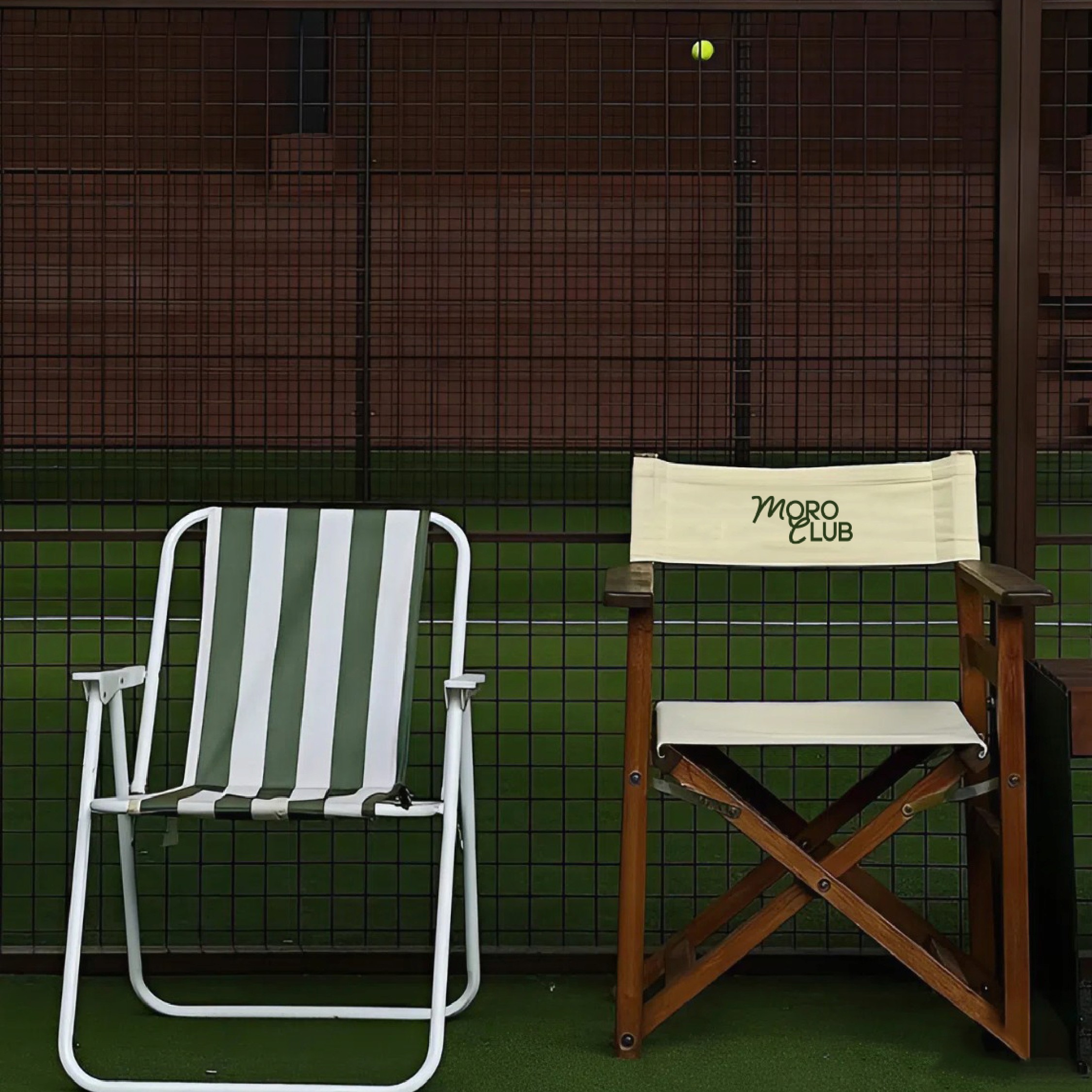 Close-up of a yellow tennis ball sitting on a green court, positioned near the white center line.