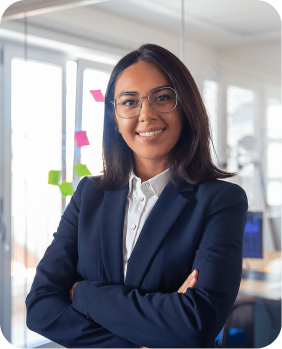 A distinguished woman with gray hair, dressed in a sharp blue suit and white shirt, speaks confidently into a microphone, conveying professionalism and expertise in a formal setting.