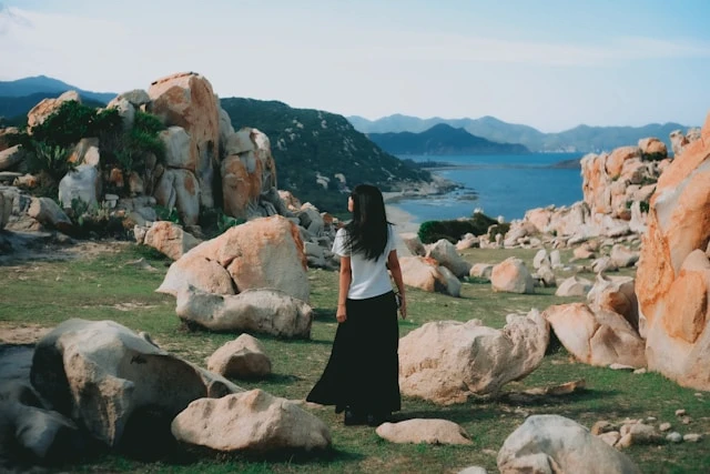 Woman standing on a rocky coastal landscape overlooking the sea