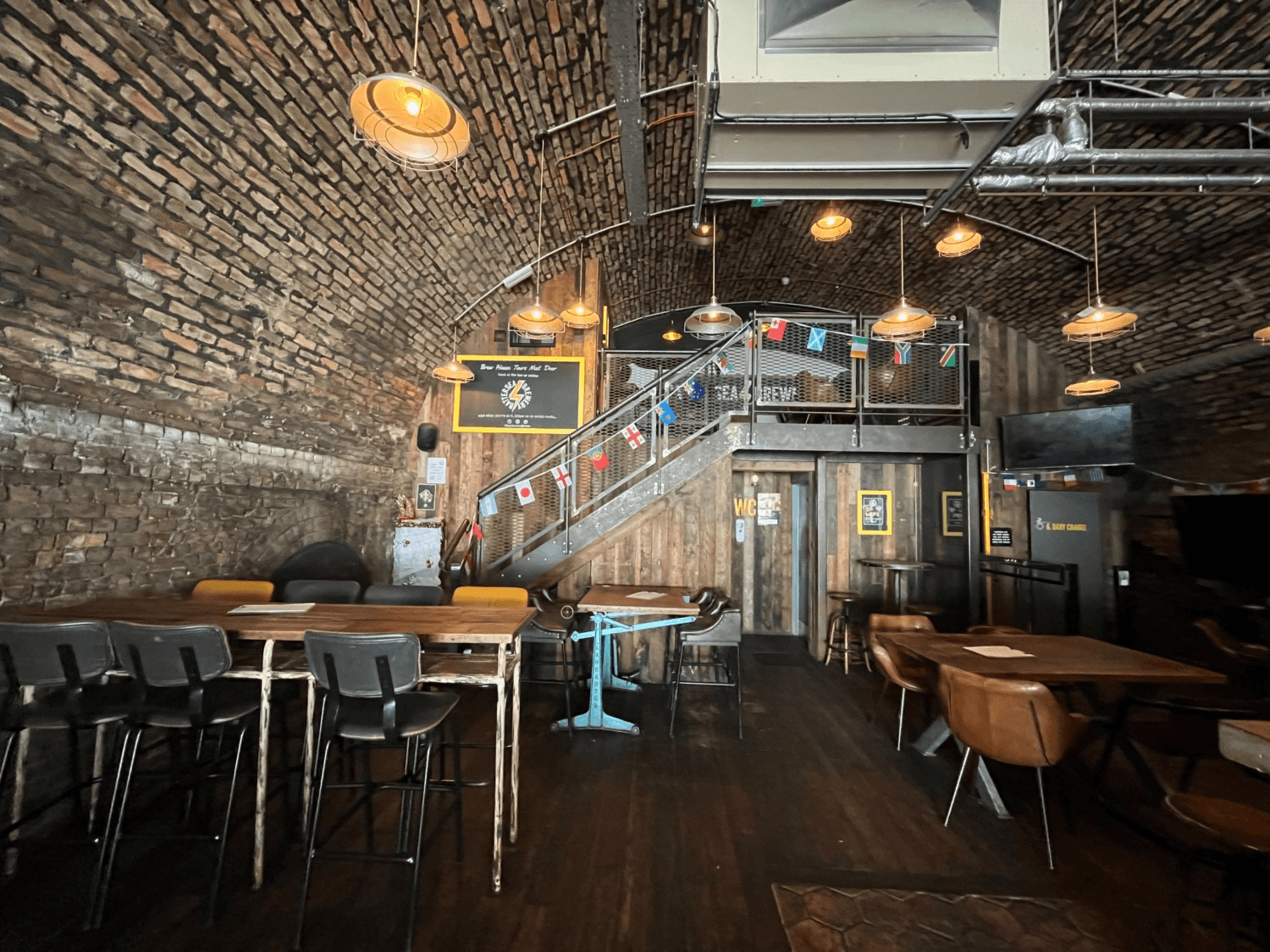 Tables and chairs at Battersea Brewery. Path in centre to wheelchair accessible toilet.