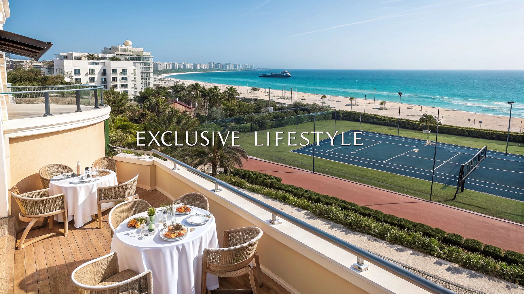 Luxurious balcony dining overlooking a vibrant beach, blue ocean, and a tennis court.