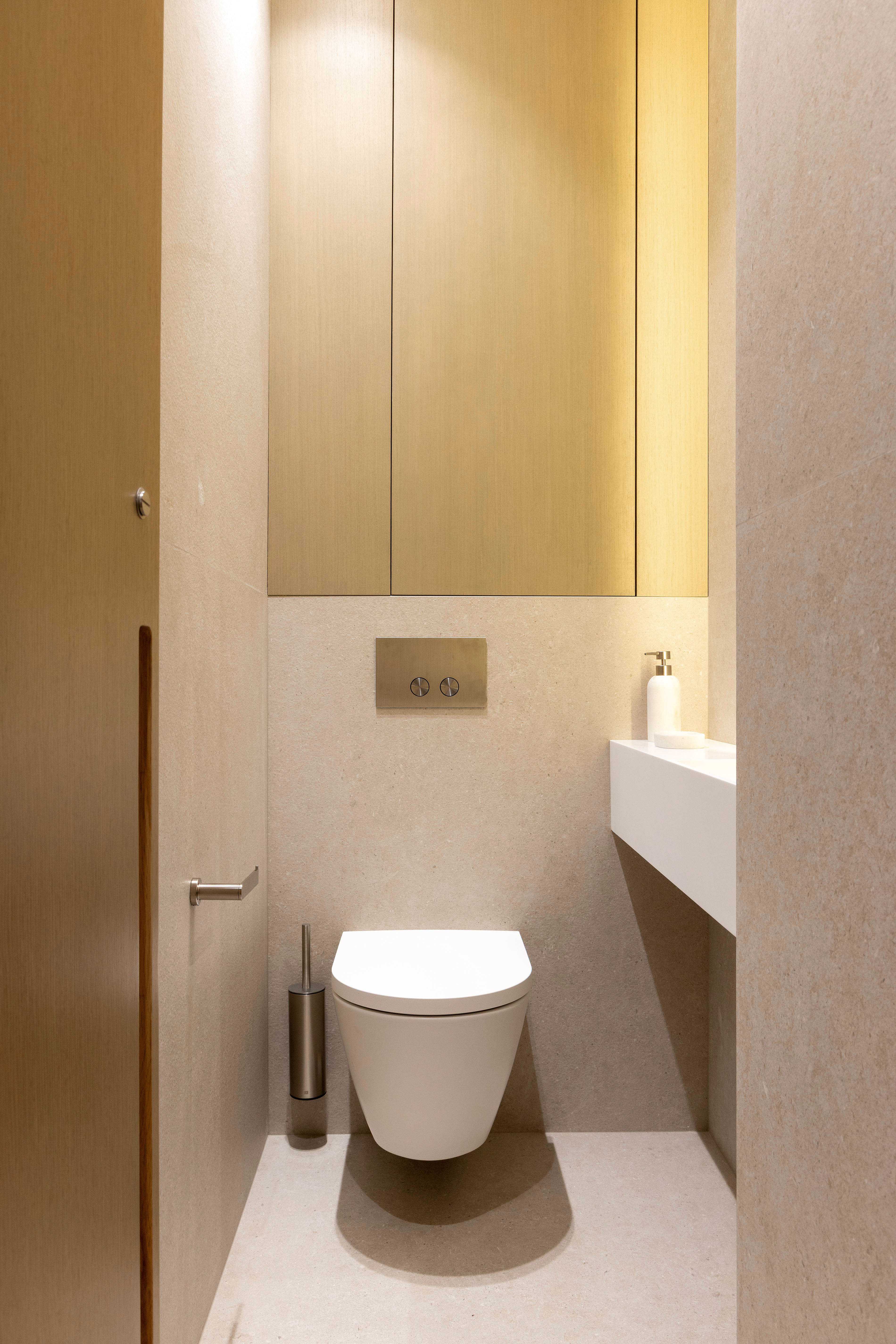 WC separe avec cuvette suspendue, placard en bois clair et petit lave-mains blanc