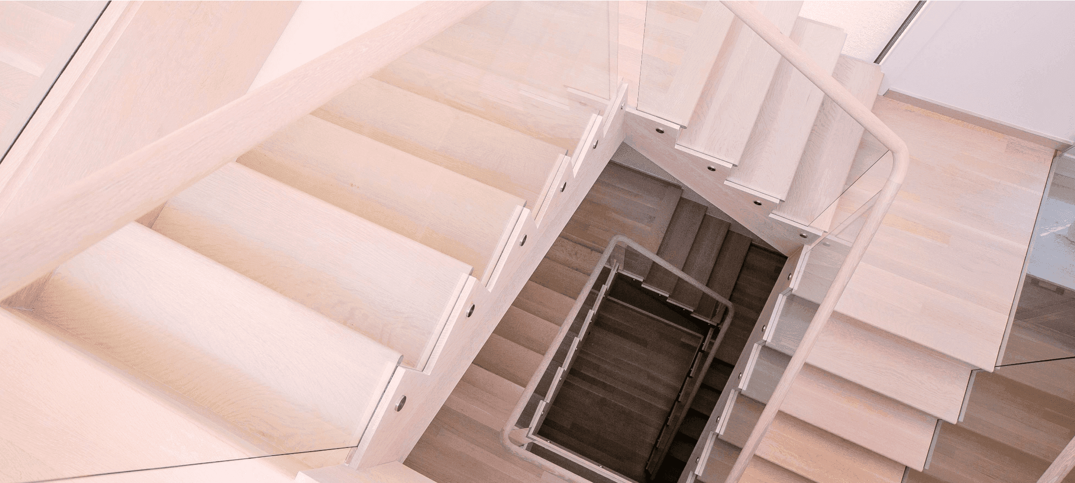 Looking down a white oak stair with square-edge treads and a frameless glass rail.