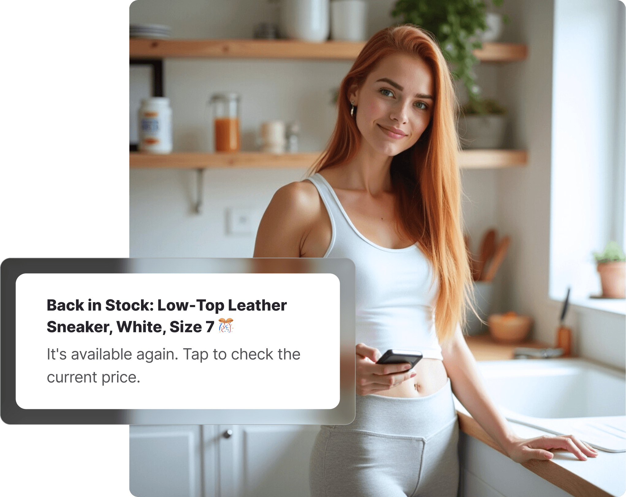 Woman in JD Sports-style athletic wear leaning against a kitchen counter holding her phone, receiving a back-in-stock notification for a sneaker.