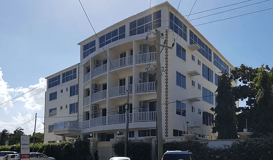 Modern brick and glass building reflecting the blue sky, with pedestrians and cyclists moving through a sunlit urban plaza, creating dynamic motion blur effects.