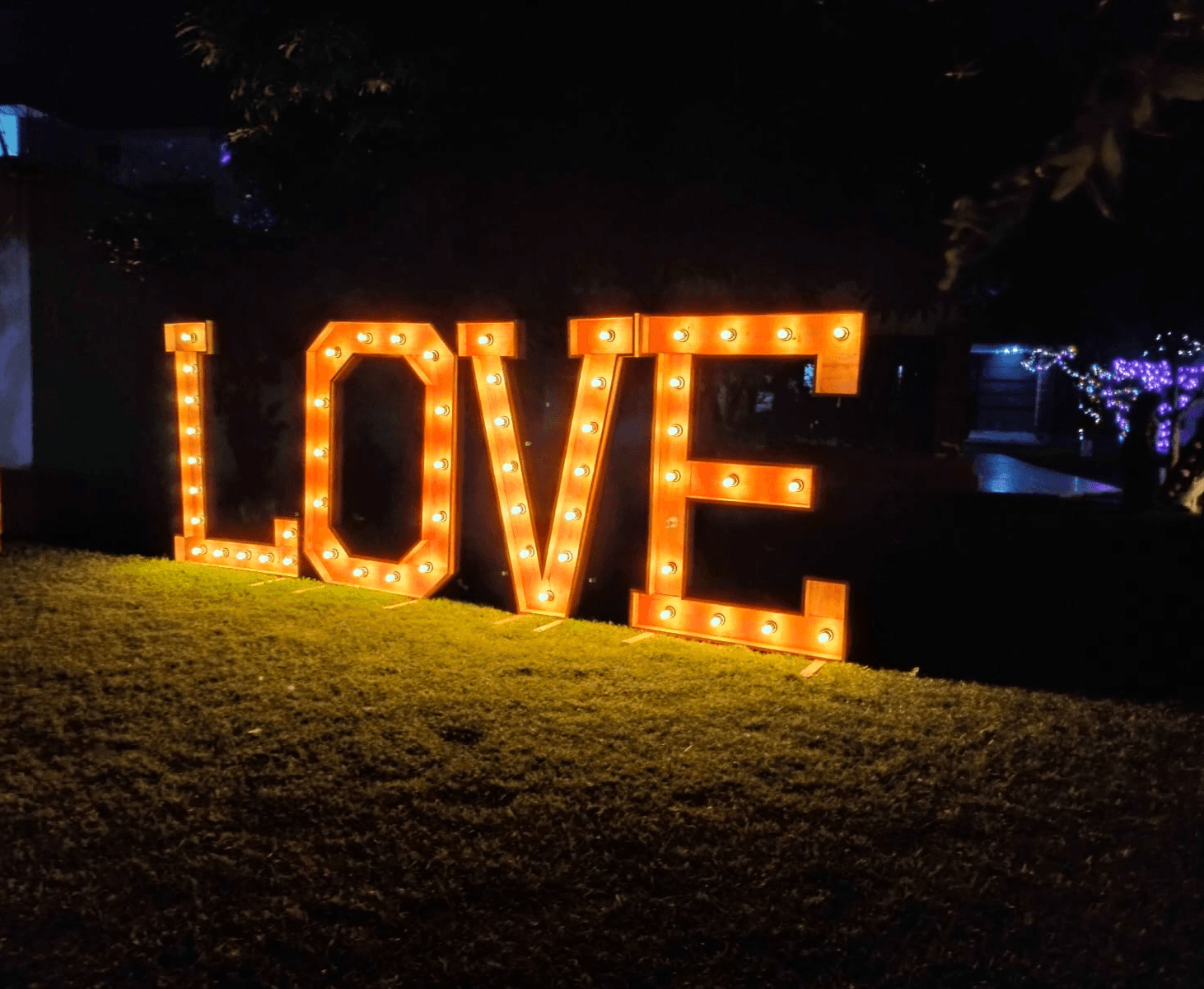 Outdoor lounge under a wooden pergola, draped linen curtains, beige cushions, ocean backdrop, palm shadows dancing on the walls, serene luxury.