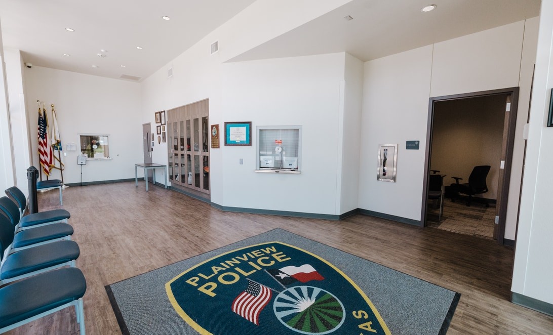 Lobby with flags, trophy case, and interview room at Plainview Police Headquarters, by Martinez Architects.