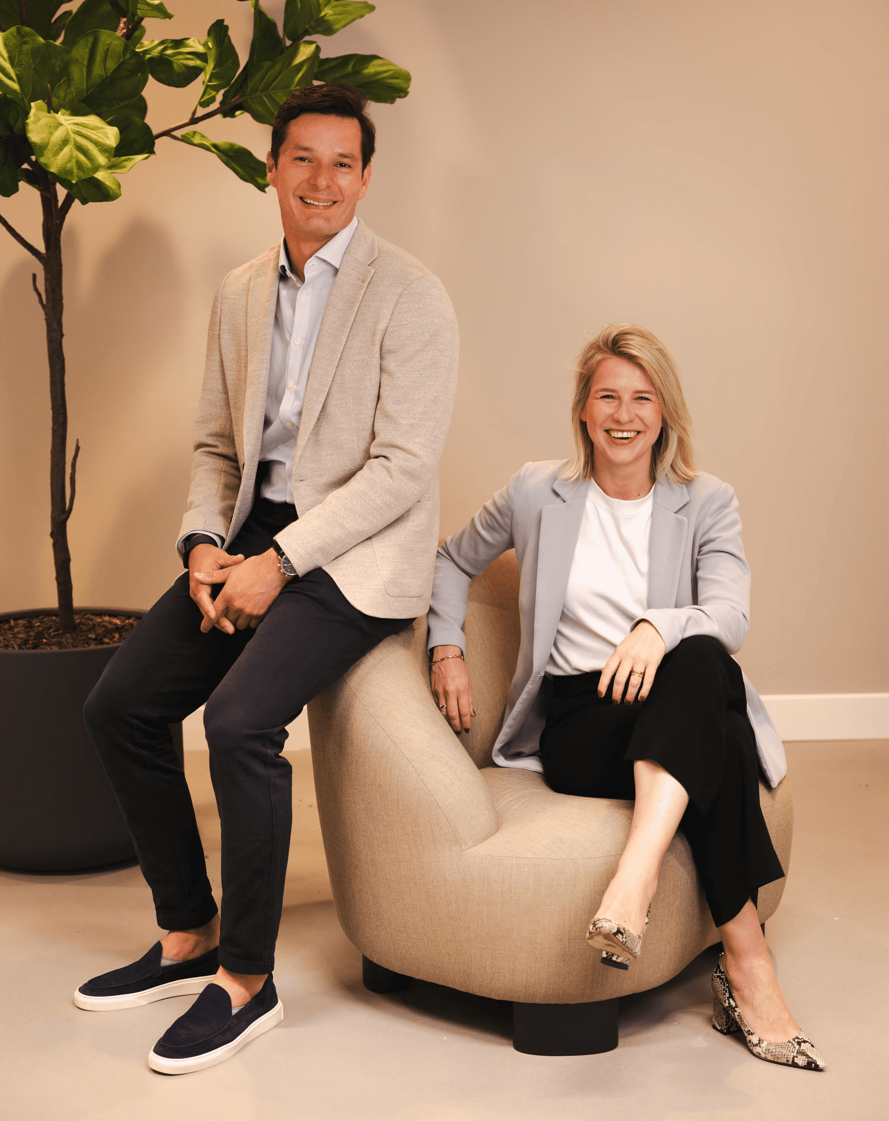A modern restaurant with a teal coffered ceiling, white curtains, large windows, dark leather chairs, wooden tables, and a white dome lamp on a marble counter.