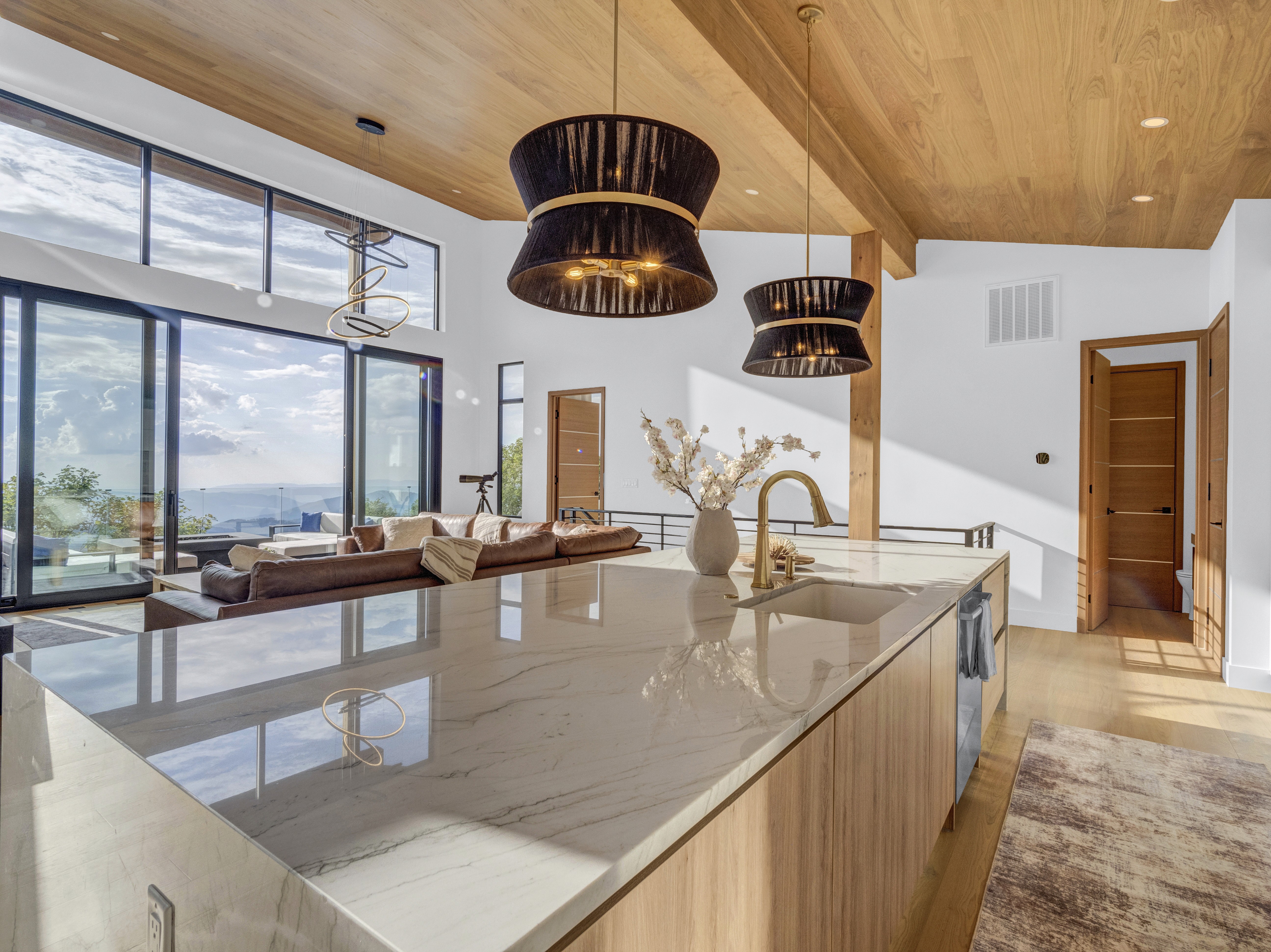 Perspective shot from the marble kitchen island looking out over the living area and the sunset through the glass doors