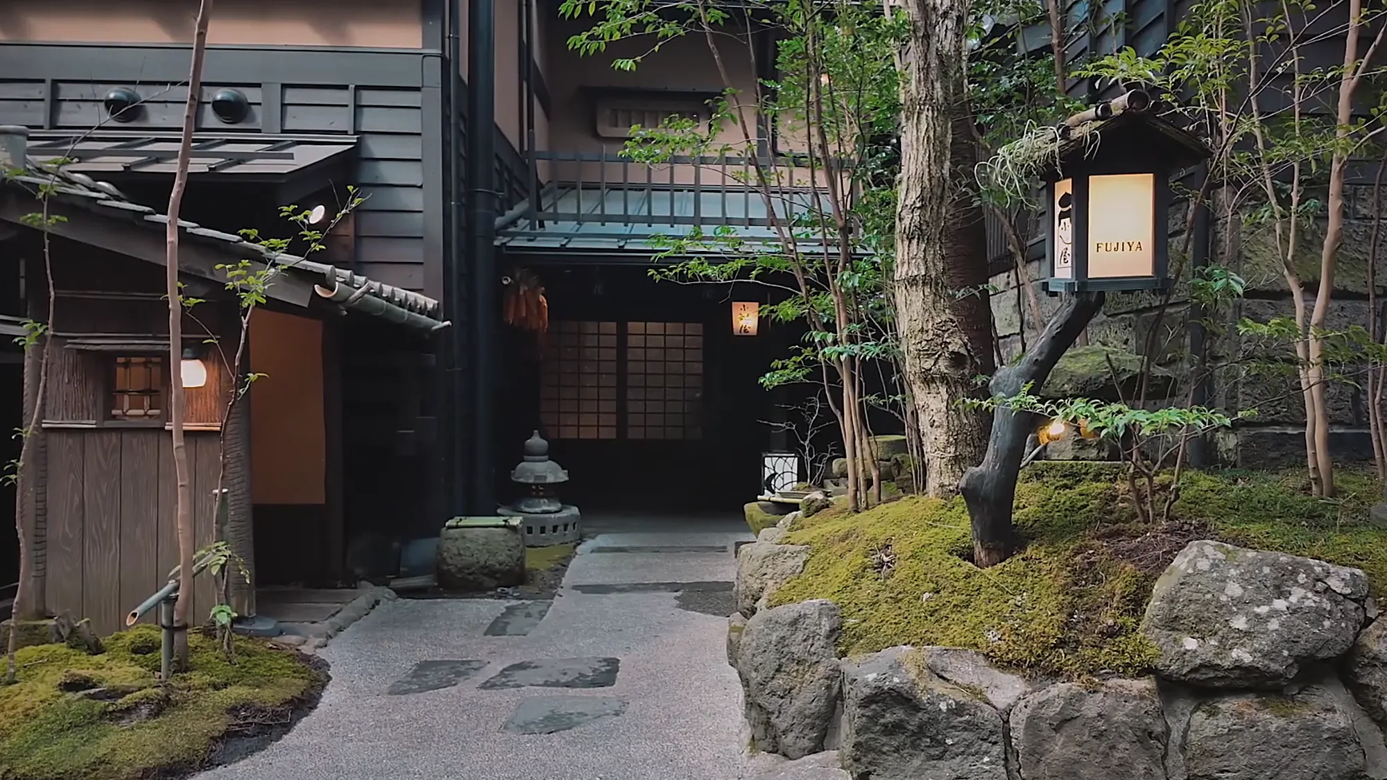 The mossy stone approach to Fujiya at Kurokawa Onsen, the inn's banner beside the path
