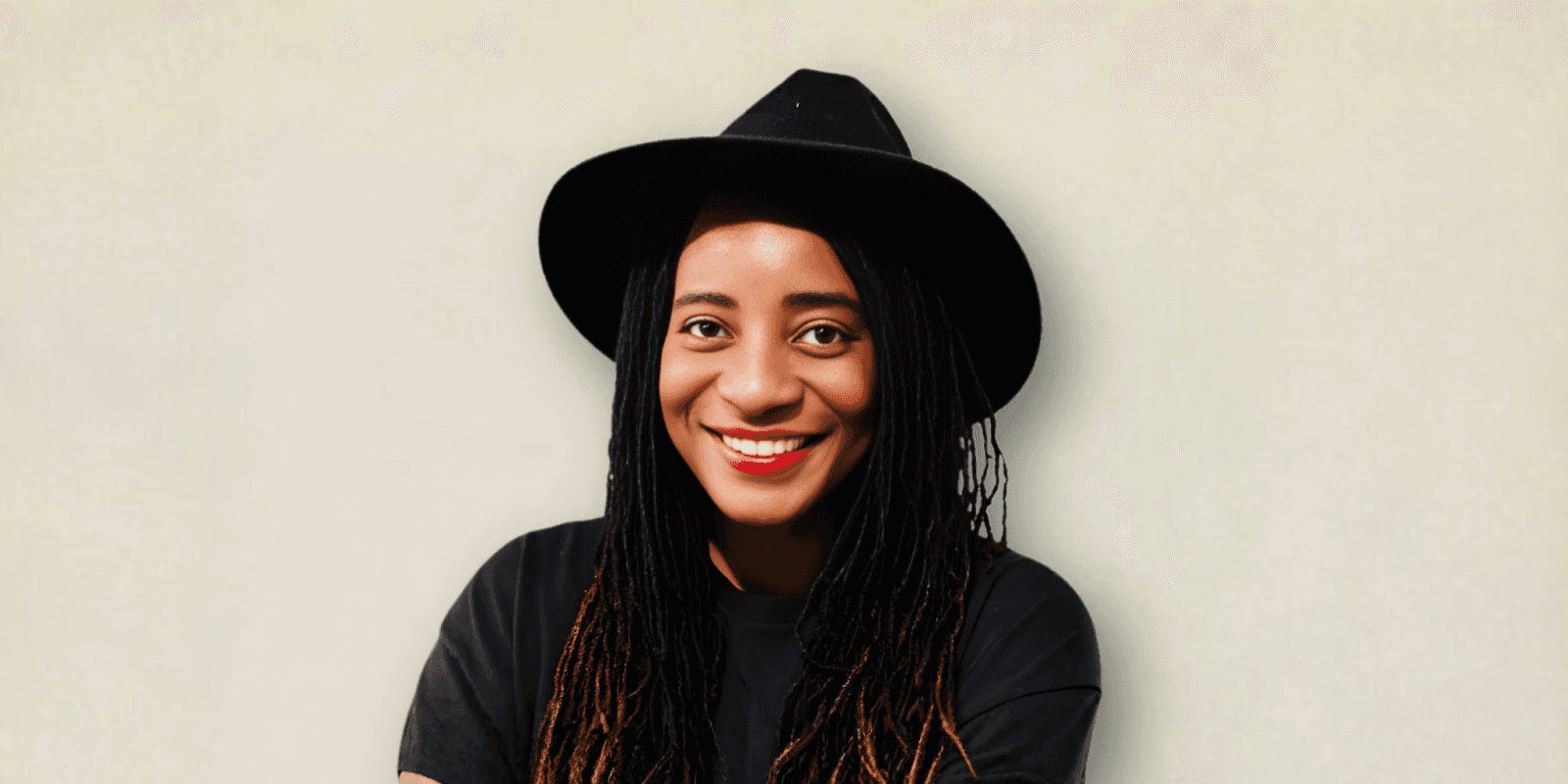 A smiling woman wearing a black hat, promoting self-care and wellness through her work, as outlined by Cheri Darling.