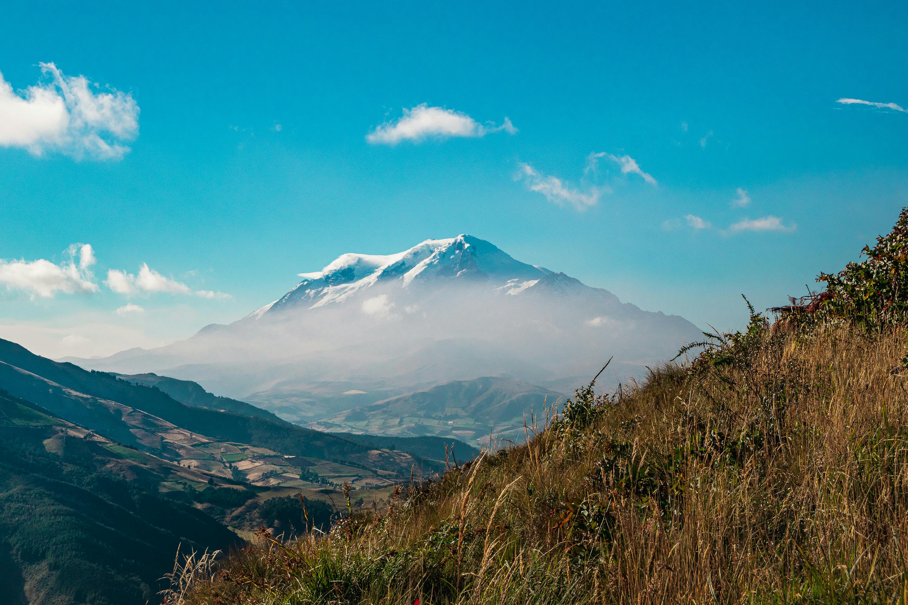 a large snow covered mountain towering over a city