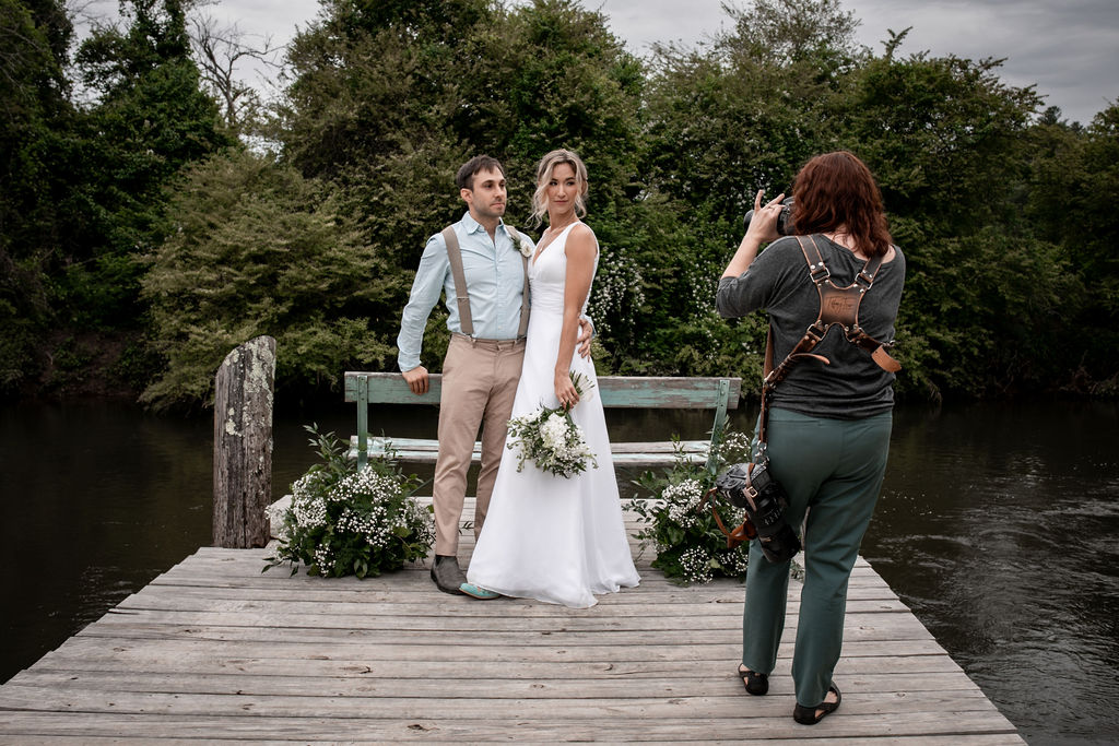 Couple on wooden dock posing for wedding photos. Photographer captures the moment.