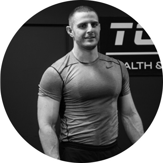 Editorial portrait of a young man with wavy hair in a knit sweater, looking over his shoulder in soft light.