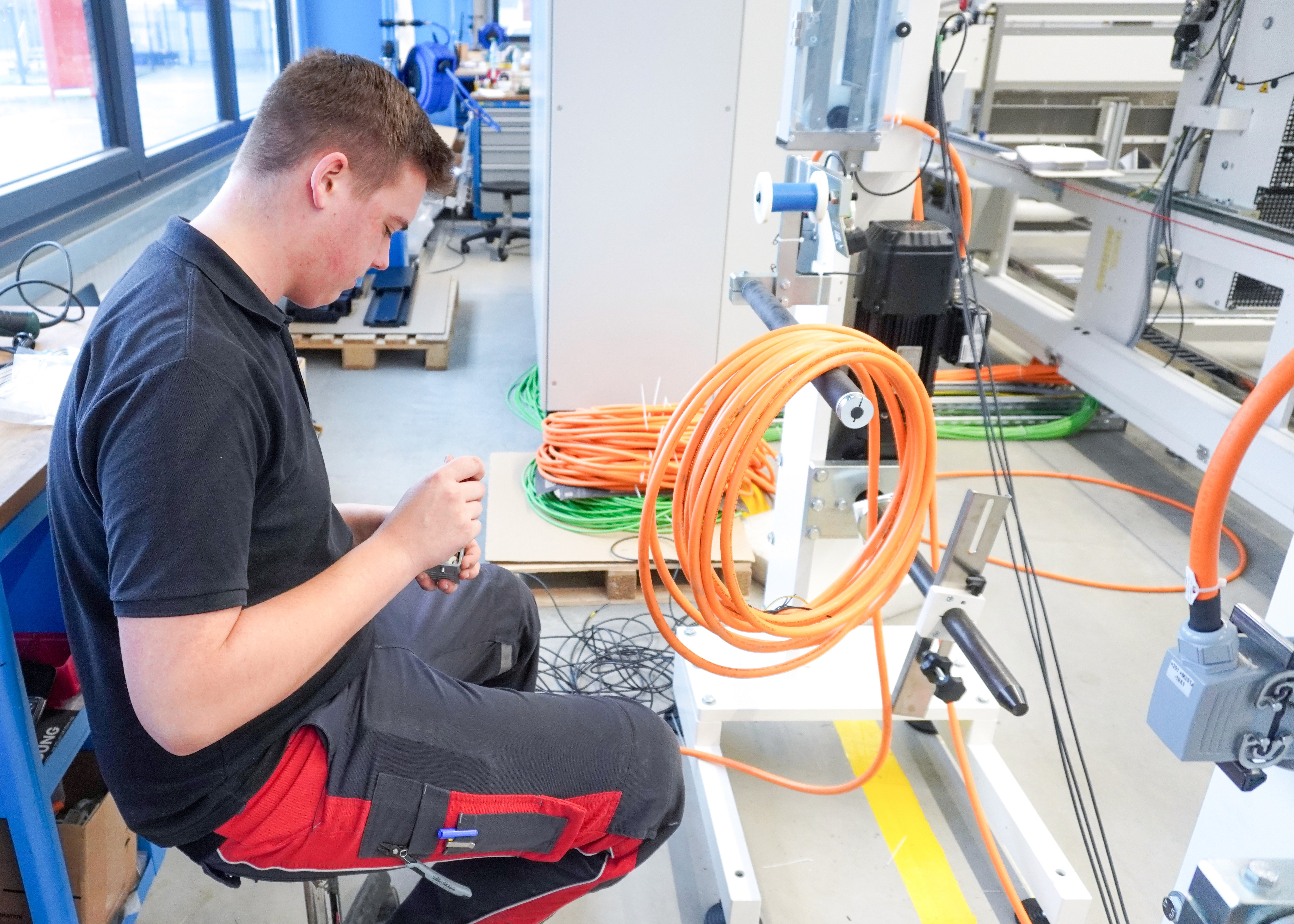 Technician at work in a workshop. Electrician installing cables. Vocational training.